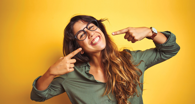 Woman smiling pointing at mouth